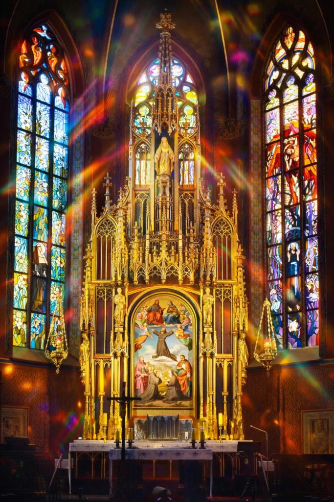 Main altar of St. Francis of Assisi Church in Krakow illuminated by colourful light reflections from stained glass windows.