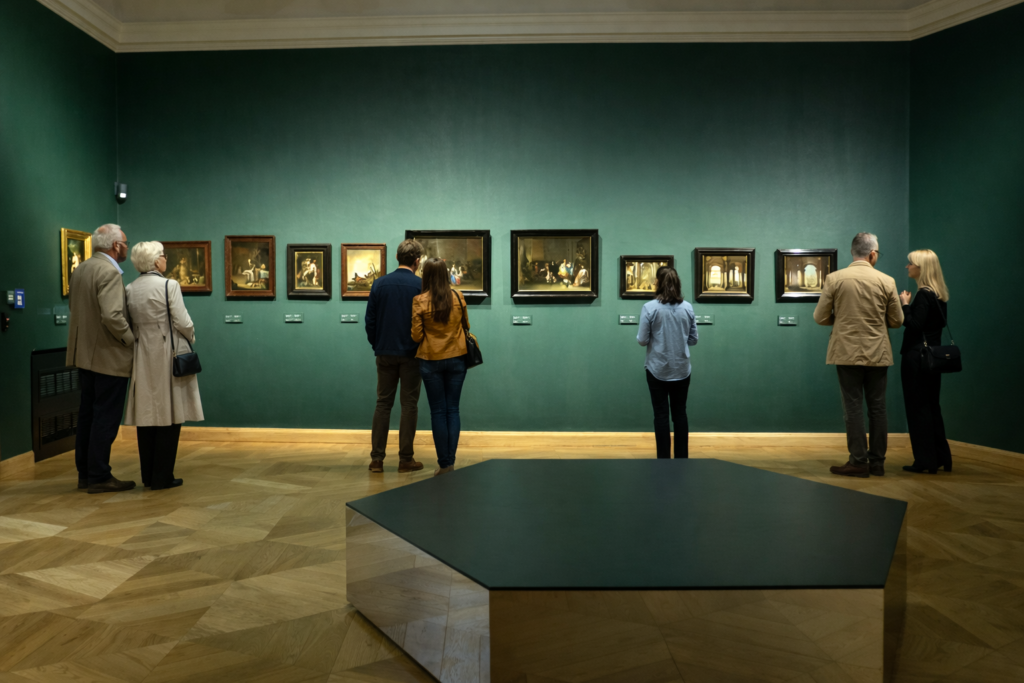 Visitors viewing artworks inside the Czartoryski Museum in Krakow, standing in front of a gallery wall with framed paintings.