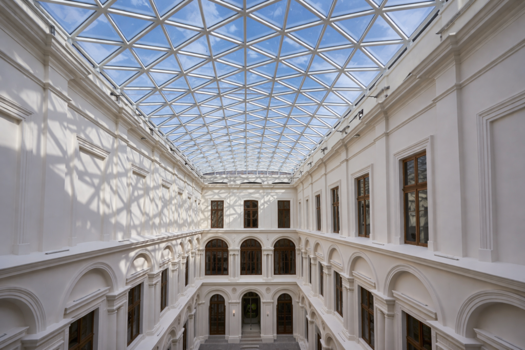 Interior courtyard of a historic building in Krakow with a glass roof and symmetrical architecture, seen from the centre.