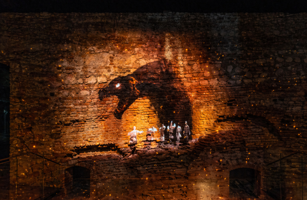 Multimedia exhibition in Międzymurze at Wawel featuring a dramatic dragon projection on historic brick walls.