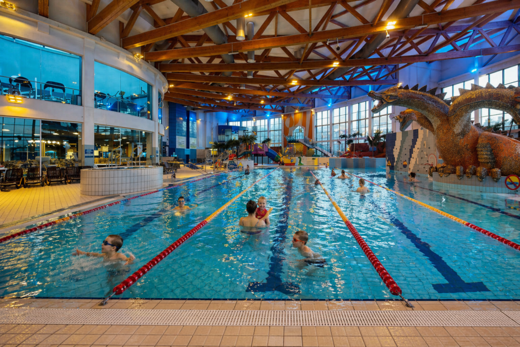 Indoor pool at Park Wodny in Krakow with swimmers, bright lighting and large dragon slide