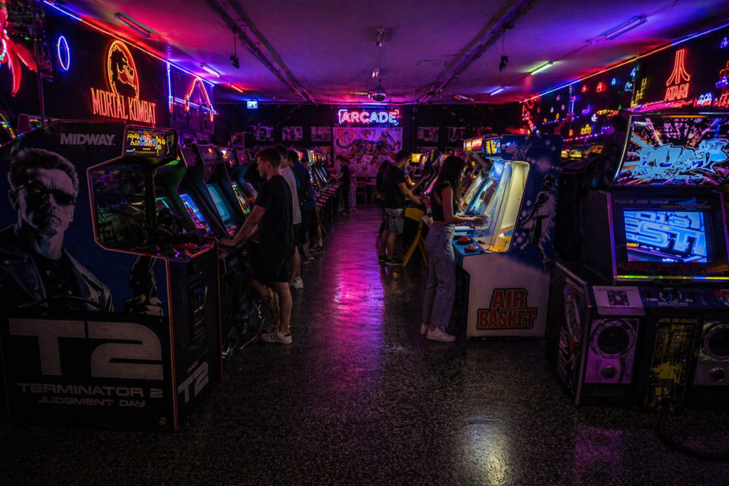 Krakow arcade museum – retro gaming hall with neon lighting and visitors playing classic arcade machines