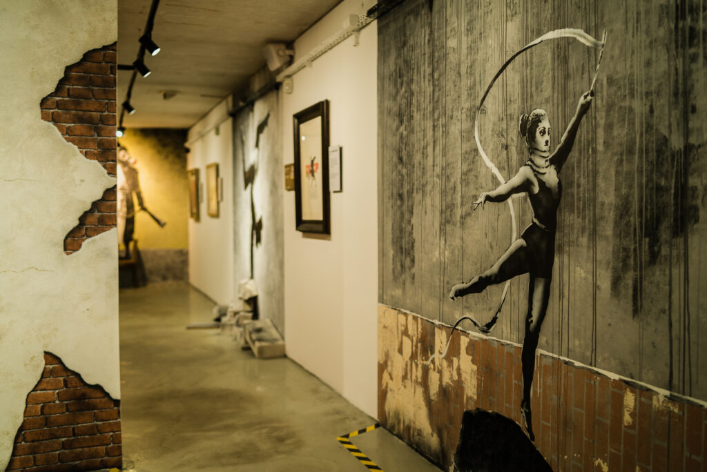 Interior exhibition at Banksy Museum Krakow featuring street art installations and recreated works in a modern gallery space.