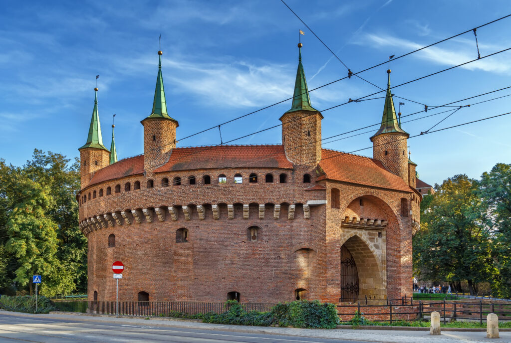 Krakow Barbican exterior with circular red-brick walls and defensive towers under a clear sky.